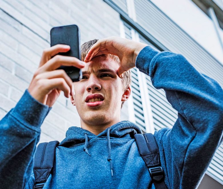 Teenager schaut verstört in sein Smartphone.