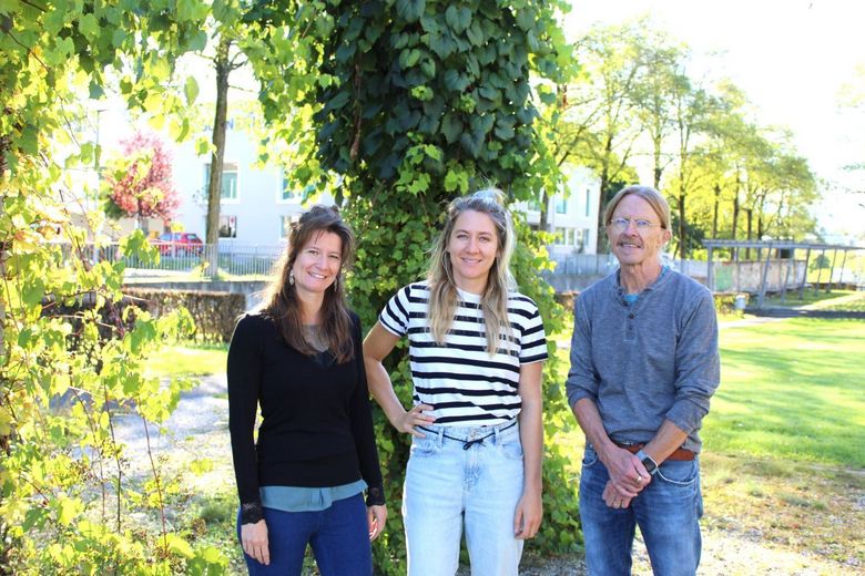 Zwei Frauen und ein Mann im Porträt, die gemeinsam an einem Lehrmittel arbeiten.