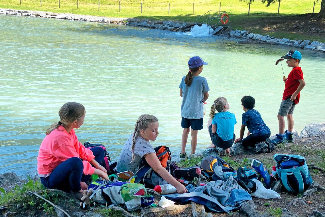 Kinder essen ihr Picknick am Ufer eines Bergsees.