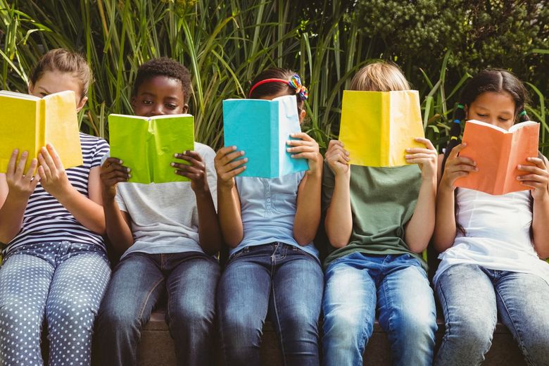 Fünf lesende Kinder in einer Reihe sitzend