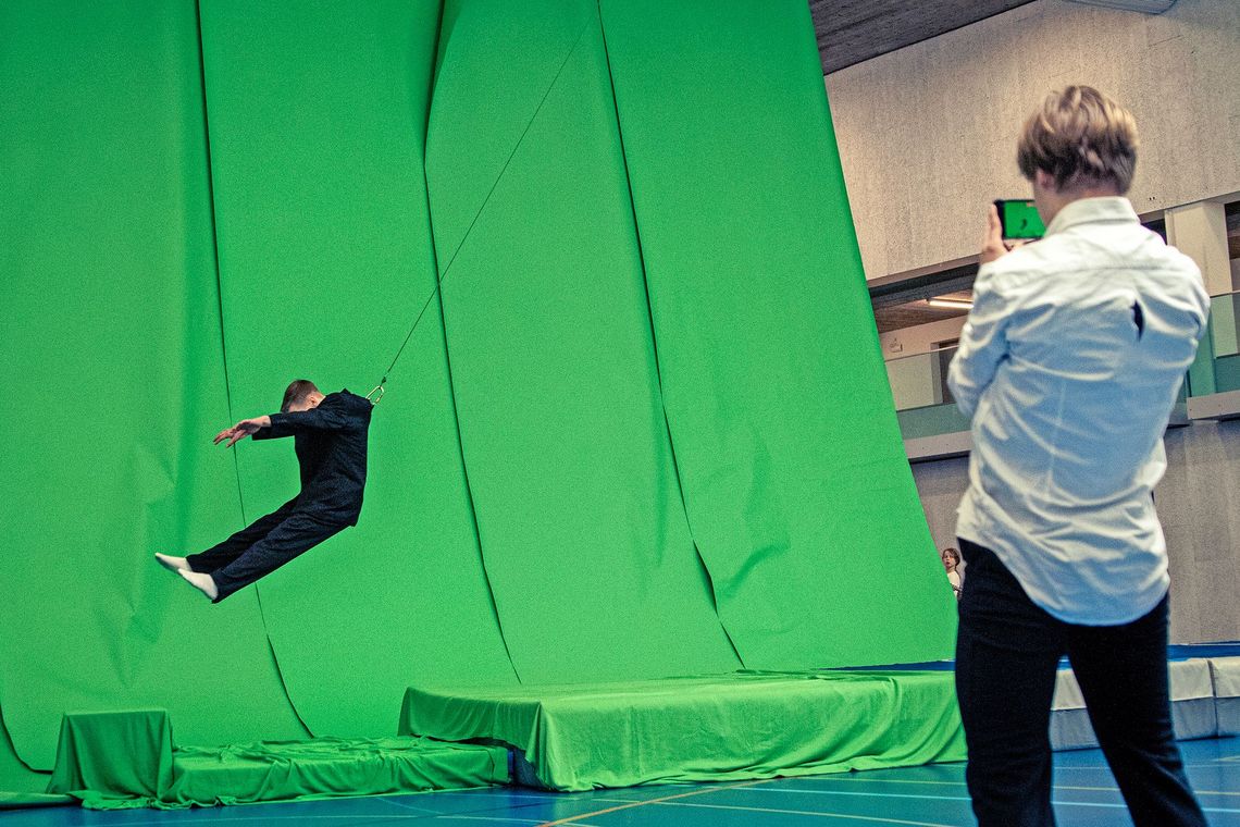 Vor einer grünen Wand hängt ein Schüler in der Luft.