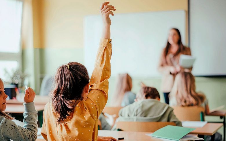 Schulkinder strecken Arme in die Höhe.