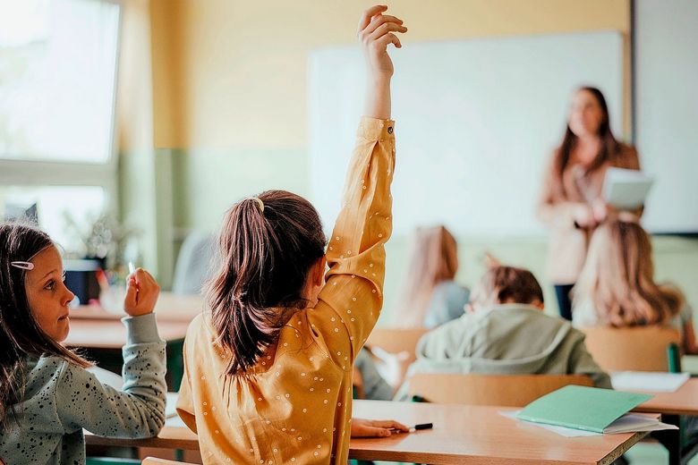 Schulkinder strecken Arme in die Höhe.