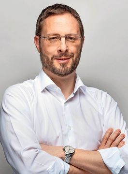 Bernhard Altermatt hat die Arme verschränkt und lächelt.