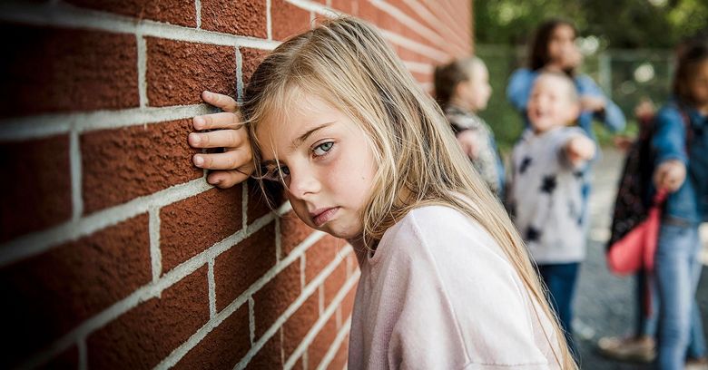 Mädchen lehnt sich an eine Backsteinmauer