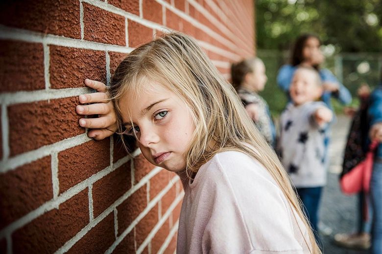 Mädchen lehnt sich an eine Backsteinmauer
