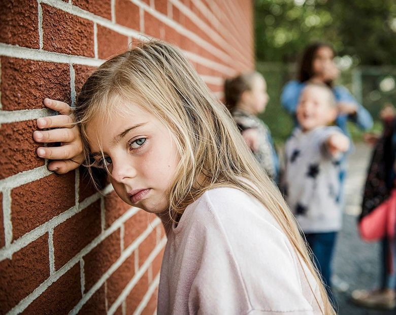 Mädchen lehnt sich an eine Backsteinmauer
