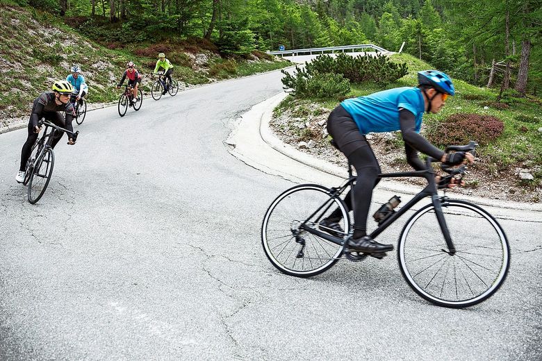 Eine Gruppe von Velofahrerinnen und Velofahrer rast eine Kurve hinunter. Foto: istock/tomazi