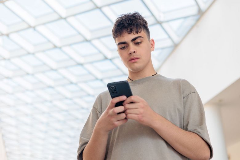 Jugendlicher tippt auf seinem Smartphone herum.