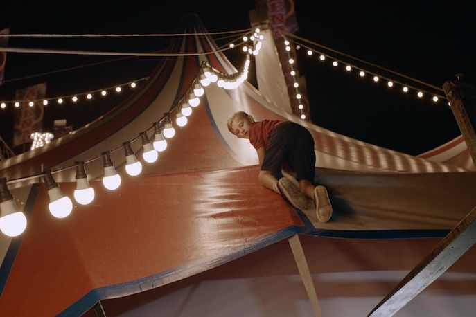 Ein kleiner Junge klettert auf einem Zirkuszelt herum.
