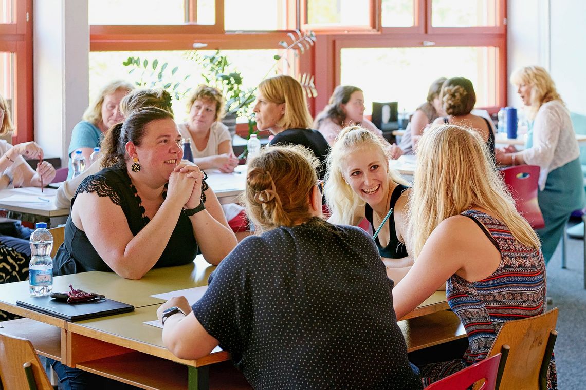 Eine Gruppe von Lehrpersonen diskutiert in einem Schulzimmer.