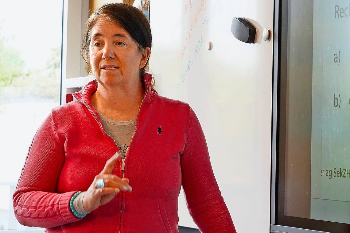 Lehrerin mit rotem Oberteil.