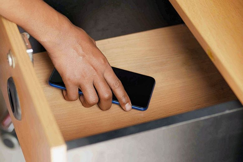 1409937974 Ein Handy wird in der Schublade versorgt.