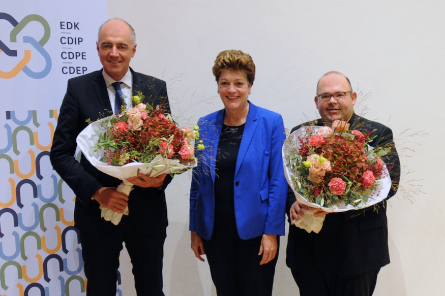 Christophe Darbellay, Silvia Steiner und Armin Hartmann lächeln. Darbellay und Hartmann halten je einen Blumenstrauss.