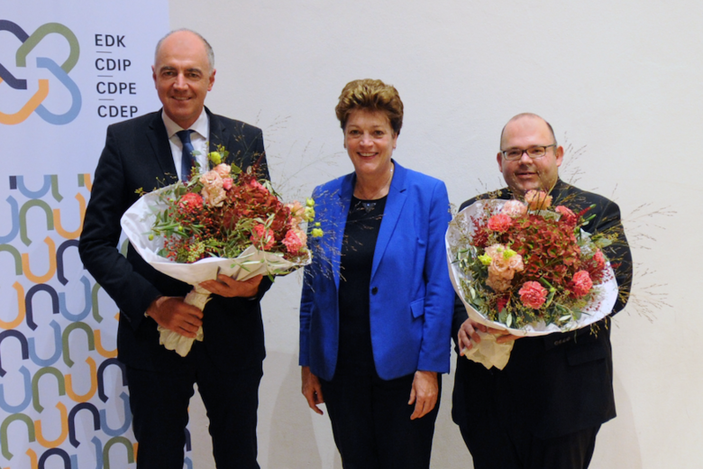 Christophe Darbellay, Silvia Steiner und Armin Hartmann lächeln. Darbellay und Hartmann halten je einen Blumenstrauss.