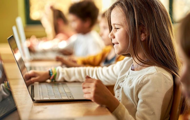 Schulmädchen sitzt vor einem Computer.