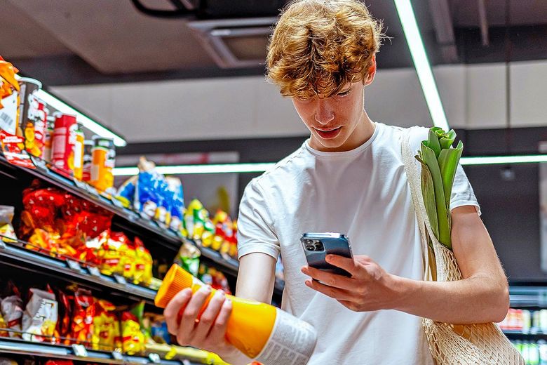 Beim Einkaufen prüft Schüler mit dem Handy, was in der Getränkeflasche drin ist.