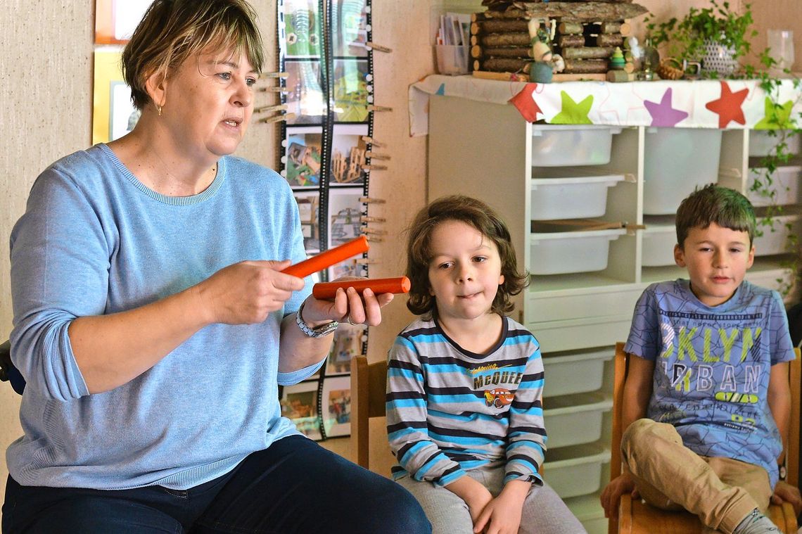 Lehrerin sitzt mit Kindern im Kreis und musiziert.