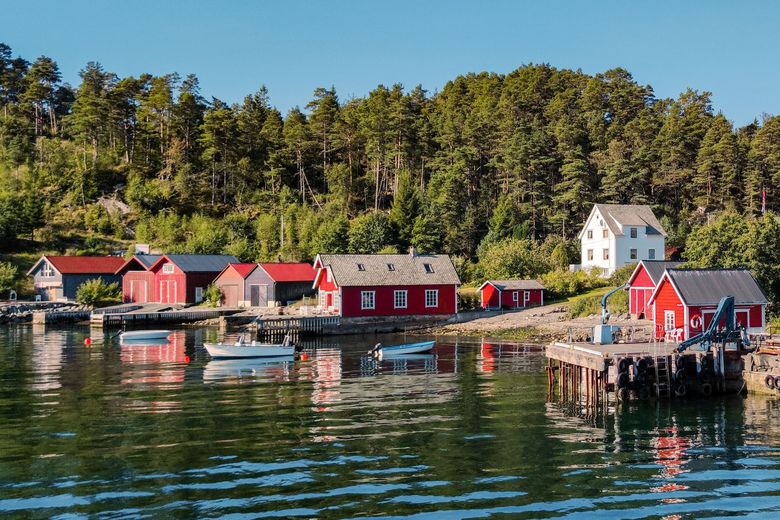 Ruhig liegt das Wasser vor einer typisch norwegischen Hafenstadt.