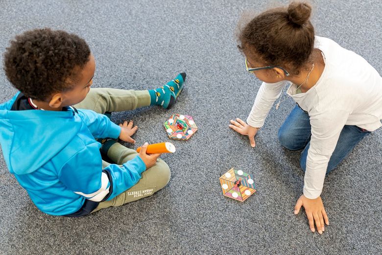 Kinder sitzen am Boden. Eines hat den Hörstift "soundolino" in der Hand.