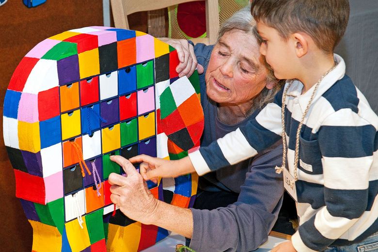 Laetitia Heinzmann zeigt einem Kind, wie es eine Schublade an einem bunten Elefanten öffnen kann.
