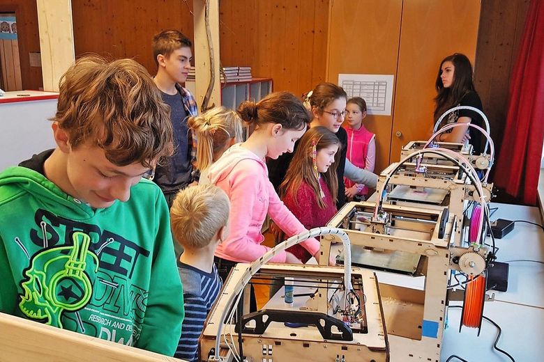 Schülerinnen und Schüler arbeiten an 3-D-Druckern.