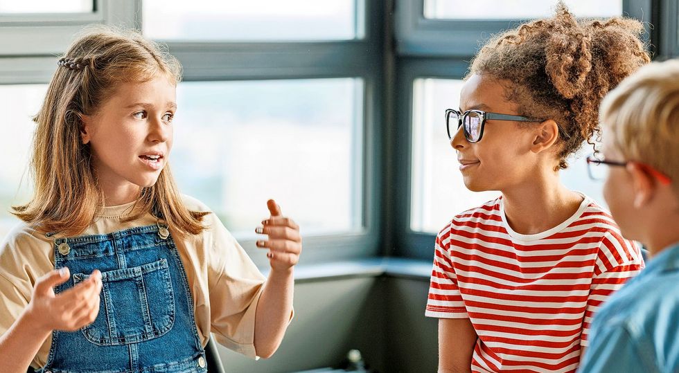 Drei Schulkinder sind in eine Unterhaltung vertieft.