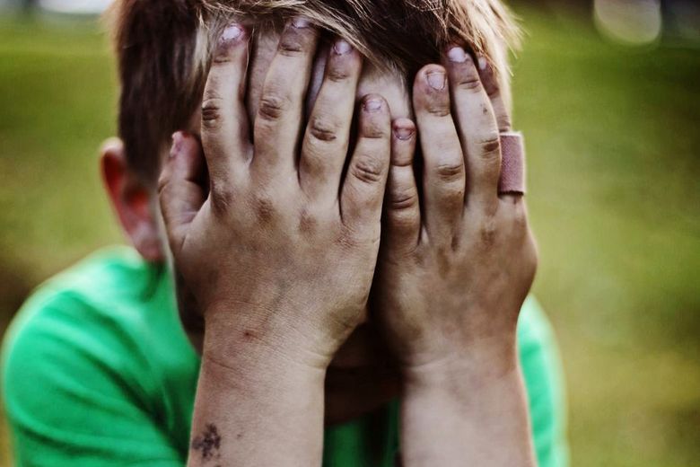 Ein Kind hat das Gesicht in seine Hände gelegt.