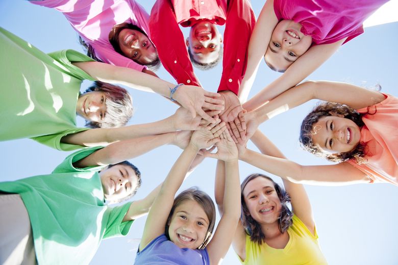 Eine Gruppe Kinder hält die Hände zusammen und lacht.