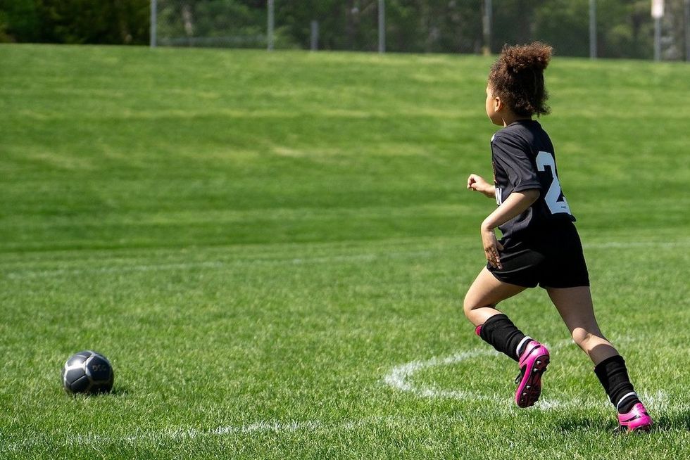 Ein Mädchen rennt auf einen Fussball zu.