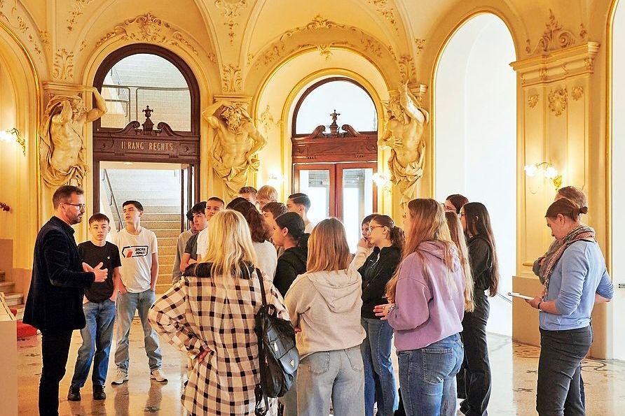 Eine Gruppe Teenager schart sich um den Führer, der ihnen mehr über das Opernhaus erzählt.