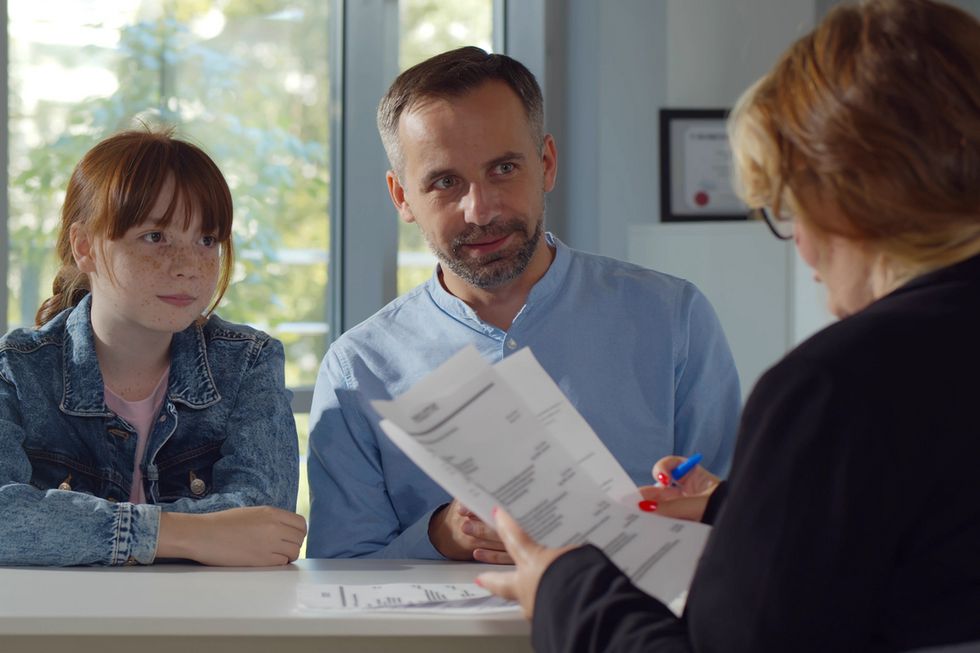 Ein Mädchen und ein Mann sitzen gemeinsam mit einer Frau an einem Tisch.