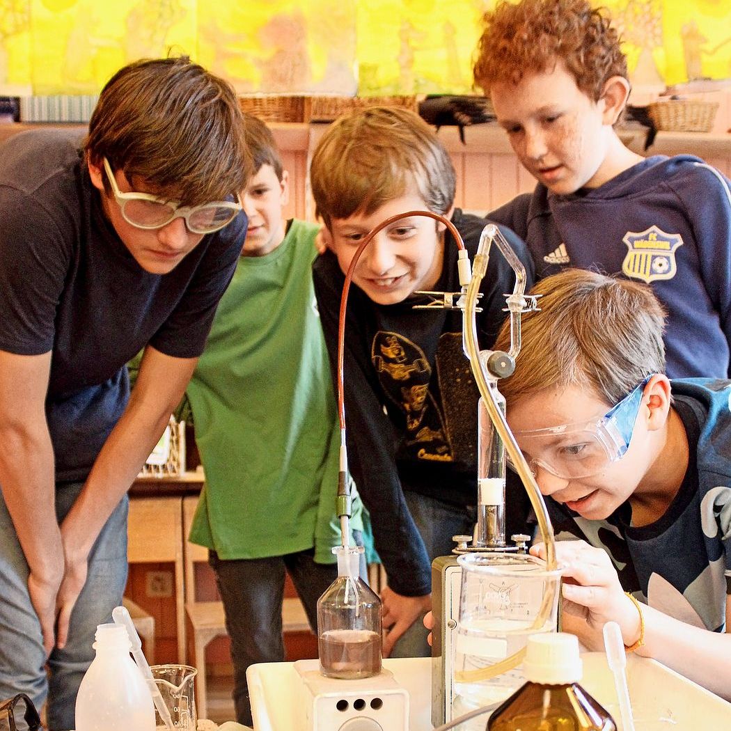 Schulkinder versammeln sich um ein Experiment.
