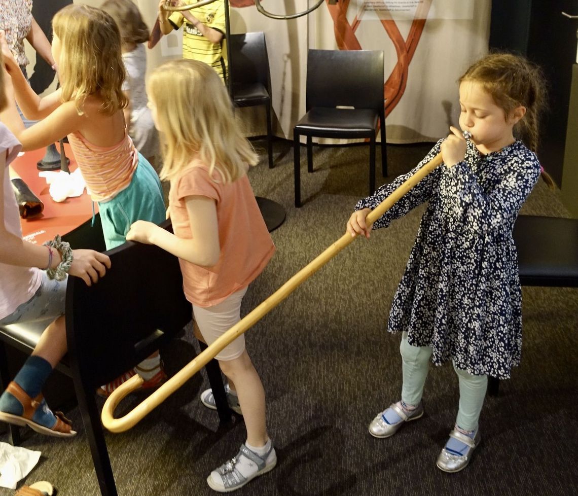 Ein Mädchen entlockt dem Alphorn-Spazierstock Töne.