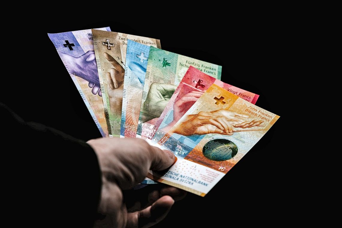 Eine Hand hält bunte Banknoten wie ein Fächer.