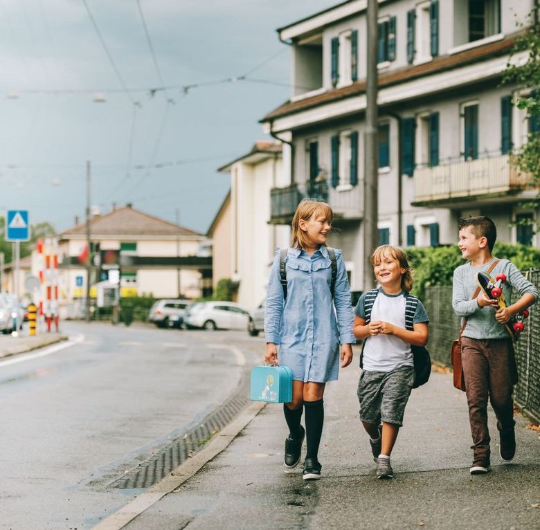 Drei Kinder unterwegs auf dem Trottoir