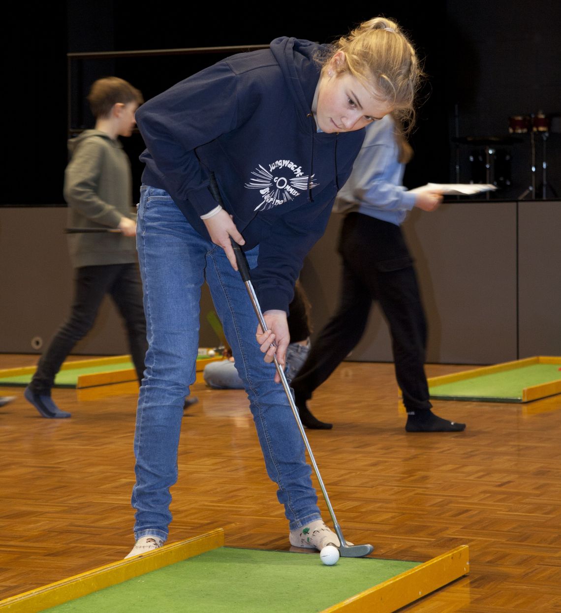 Ein Mädchen spielt Minigolf. 