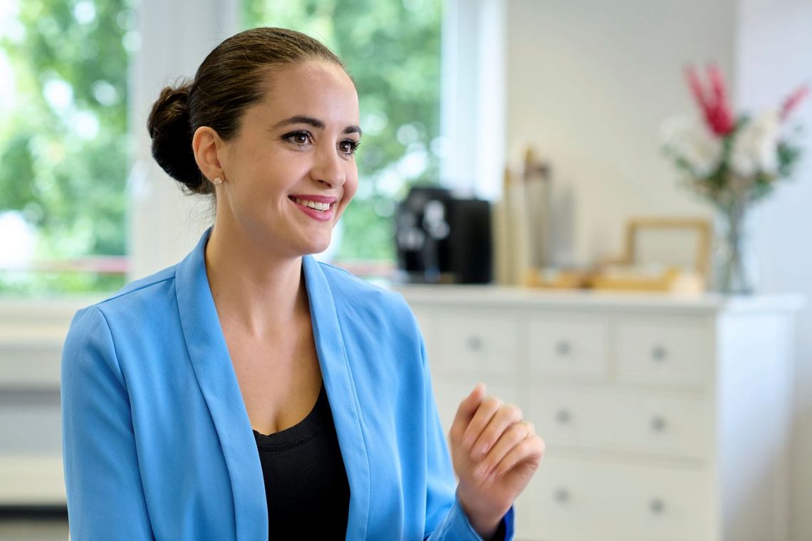 Frau mit dunklem Haar und blauer Jacke.
