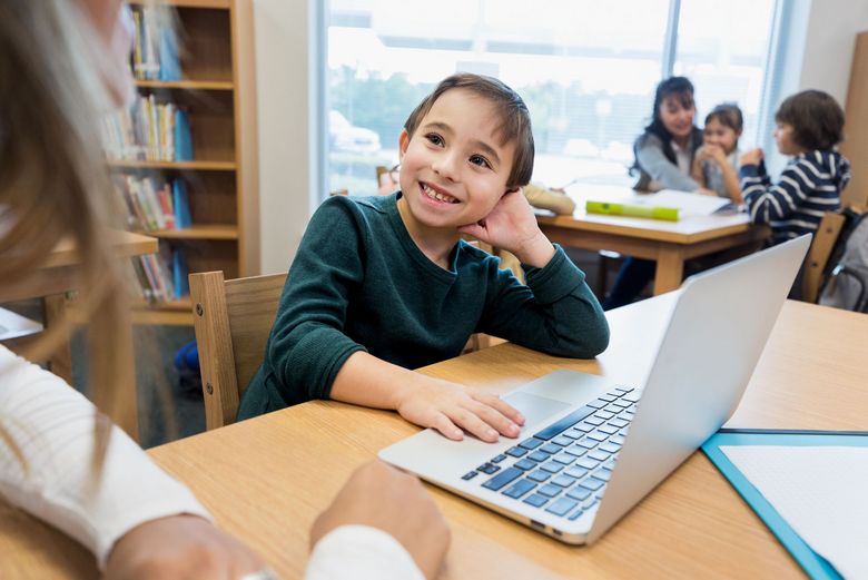 Ein Kind sitzt in der Bibliothek vor einem Laptop.