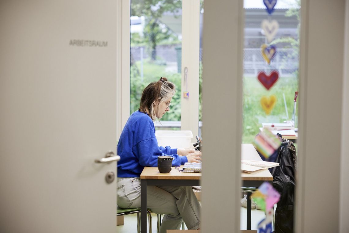 Eine Lehrerin sitzt alleine in einem Klassenzimmer und arbeitet an einem Computer.