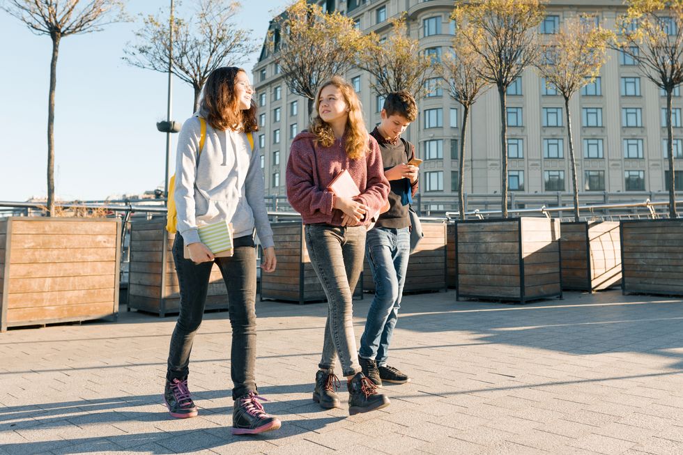 Drei Jugendliche schlendern über einen Platz.