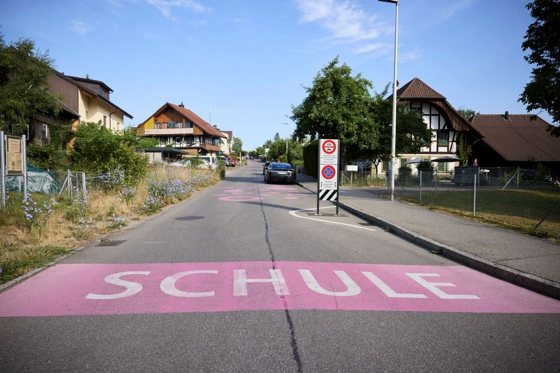 Strasse mit einem pinkfarbenen Streifen und dem Schriftzug Schule