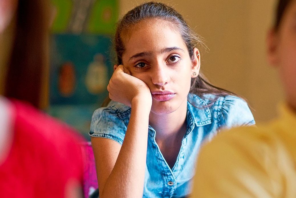 Mädchen in der Schule blickt gelangweilt in die Welt.