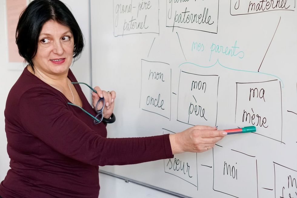 Frau zeigt mit Stift auf Whiteboard, wo französische Worte stehen