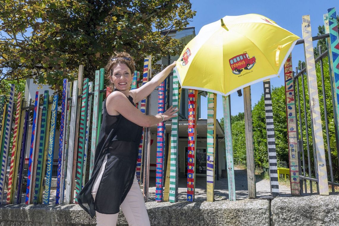 Rosina Sindoni mit einem gelben Regenschirm, auf dem das Symbol des Pedibusses abgedruckt ist. 