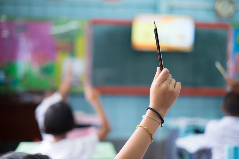 Eine Schülerin streckt mit dem Stift in der Hand auf. 