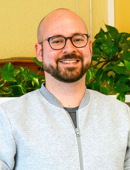 Ein Porträtfoto von Fabian Hug. Er trägt eine Brille und hat einen Bart.