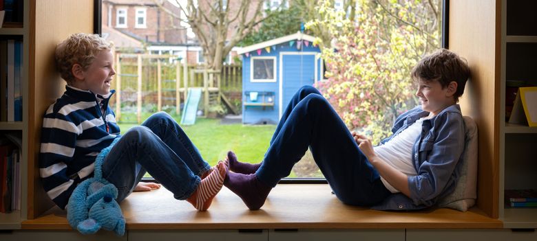 zwei Knaben sitzen auf einer Fensterbank