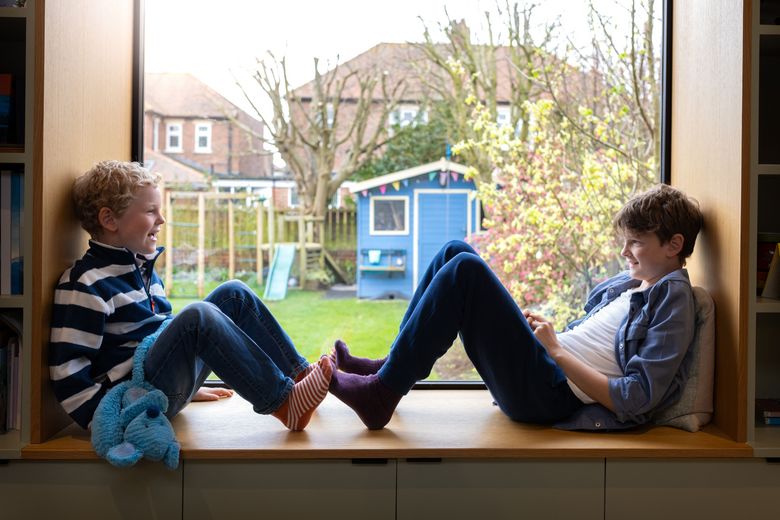 zwei Knaben sitzen auf einer Fensterbank