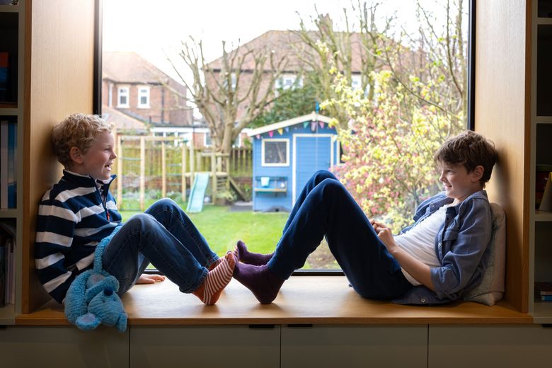 zwei Knaben sitzen auf einer Fensterbank